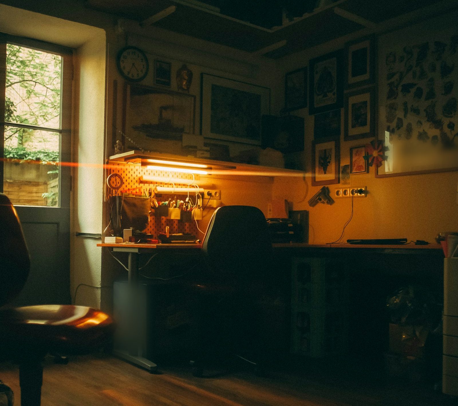 Ruhiges Tattoostudio mit Arbeitsplatz unter warmem Licht, gerahmten Motiven an der Wand und Holzboden